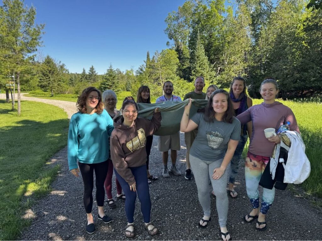 Participants carry the collaborative nature mandala to the Pigeon River during GLYTA's Living in the Light Summer Solstice Hatha Yoga Retreat at Song of the Morning.