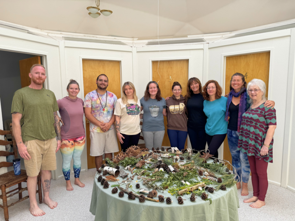 Participants gather around a collaborative nature mandala created during the Living in the Light Summer Solstice Hatha Yoga Retreat at Song of the Morning.